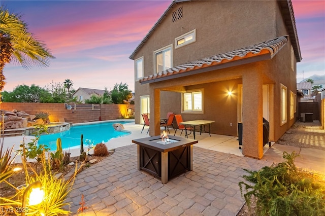 pool at dusk featuring an outdoor fire pit, a fenced backyard, a patio area, and central AC