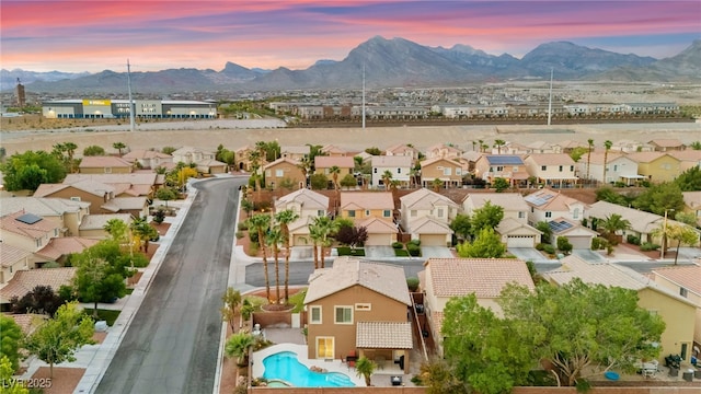 aerial view at dusk of a mountain view, a residential view, and view of pool area