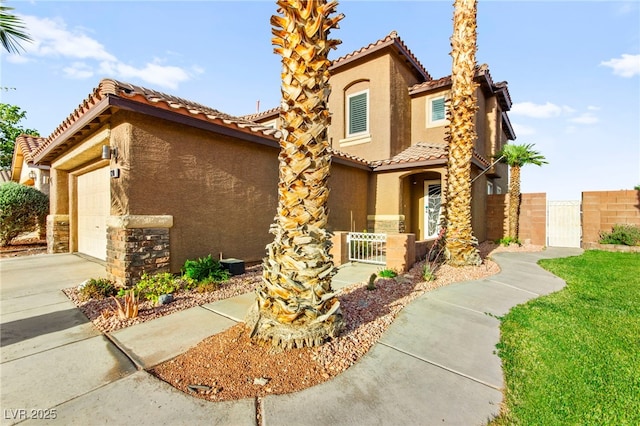 mediterranean / spanish-style home featuring a gate, stucco siding, a tiled roof, and fence