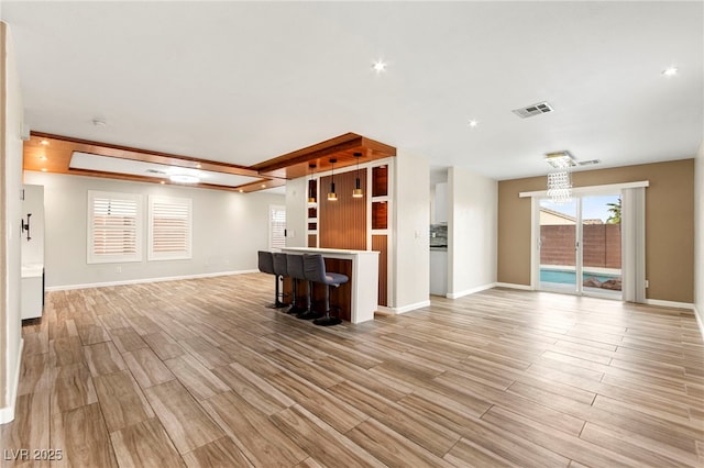 unfurnished living room featuring light wood-style flooring, baseboards, and a bar