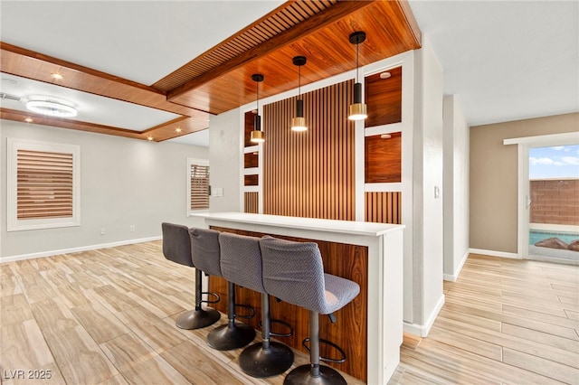 indoor dry bar with baseboards, wood finished floors, and decorative light fixtures