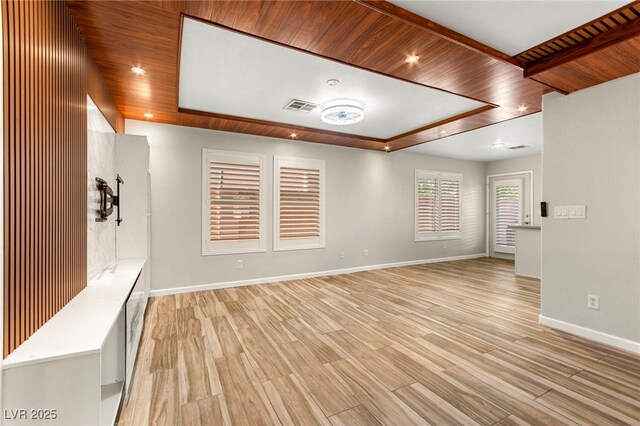 empty room featuring light wood finished floors, baseboards, and wooden ceiling