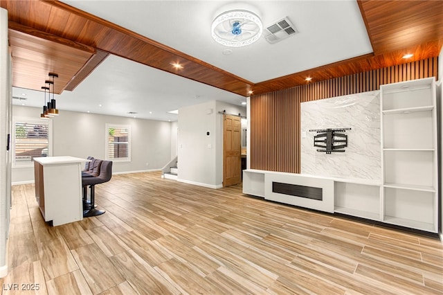 living area with baseboards, a barn door, light wood-type flooring, stairs, and built in shelves