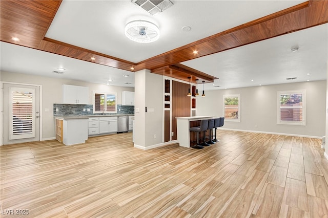 kitchen with stainless steel dishwasher, open floor plan, white cabinets, and plenty of natural light