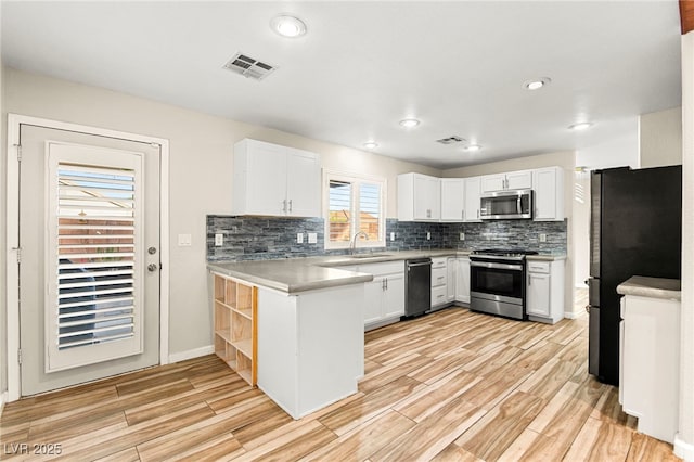 kitchen featuring appliances with stainless steel finishes, light wood finished floors, decorative backsplash, light countertops, and white cabinetry