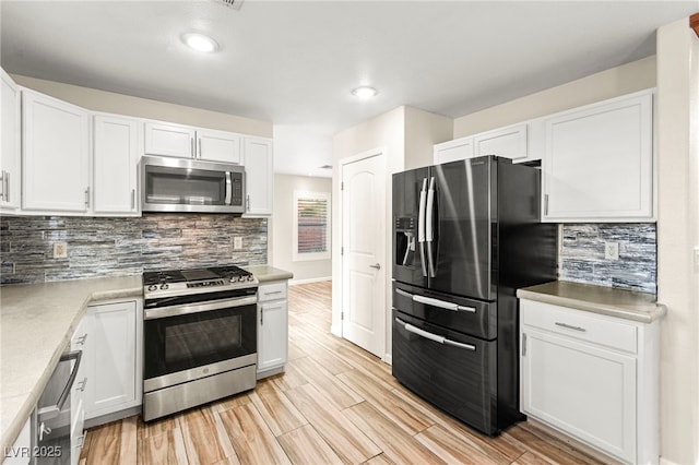 kitchen with appliances with stainless steel finishes, white cabinetry, tasteful backsplash, and recessed lighting