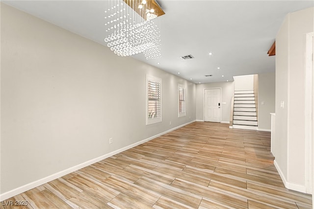 empty room with light wood finished floors, stairway, a chandelier, baseboards, and recessed lighting