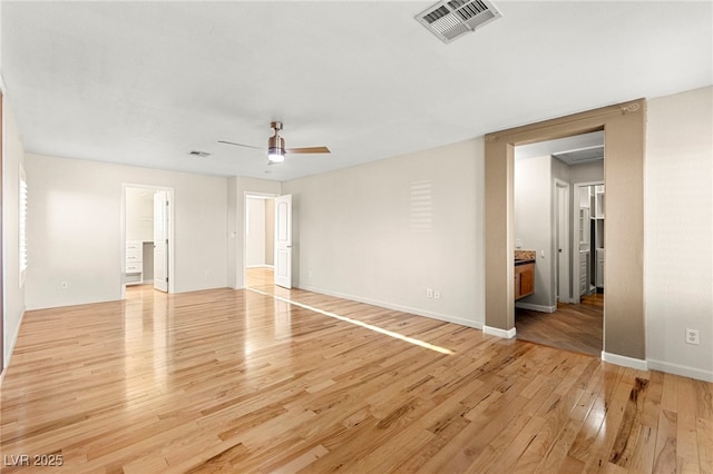 unfurnished bedroom featuring light wood-style flooring, baseboards, ensuite bathroom, and a ceiling fan