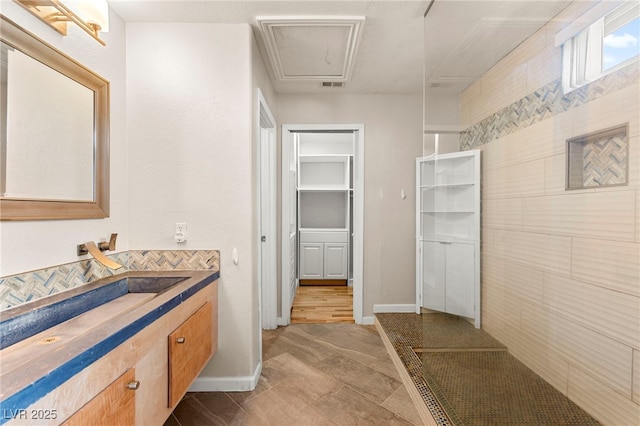 full bath with vanity, a spacious closet, and baseboards