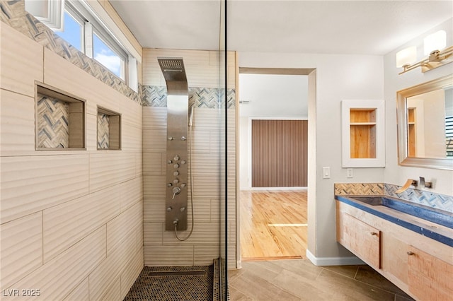 full bath with a tile shower and vanity