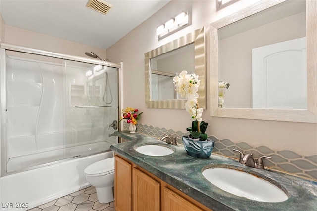 full bathroom with toilet, shower / bath combination with glass door, double vanity, and tile patterned floors