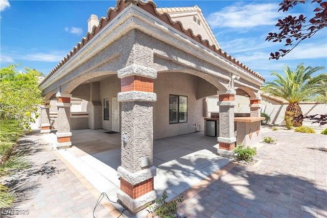 8437 Apple Hill Ct, Las Vegas, NV 89128 - view of front of home with a fireplace, a patio area, stucco siding, and a tiled roof