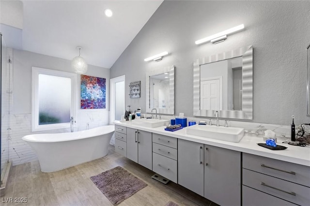 5125 Turnberry Ln, Las Vegas, NV 89113 - bathroom featuring lofted ceiling, a freestanding tub, double vanity, wood finished floors, and tile walls