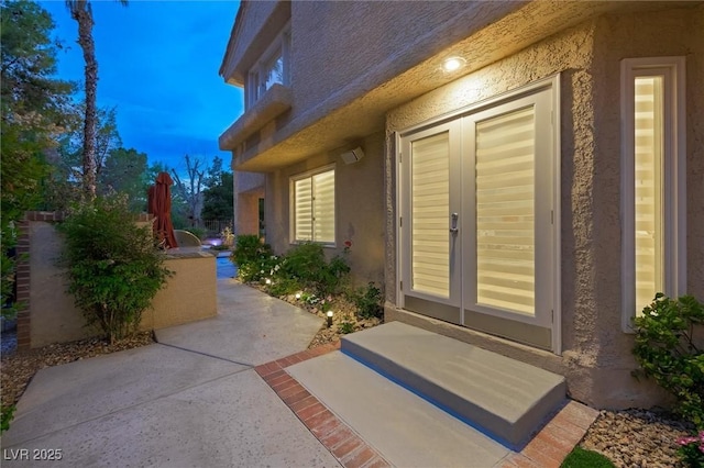 5125 Turnberry Ln, Las Vegas, NV 89113 - exterior entry at dusk featuring stucco siding, french doors, and a patio area