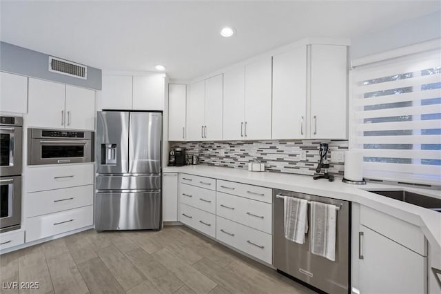 5125 Turnberry Ln, Las Vegas, NV 89113 - kitchen with stainless steel appliances, light countertops, decorative backsplash, white cabinets, and recessed lighting