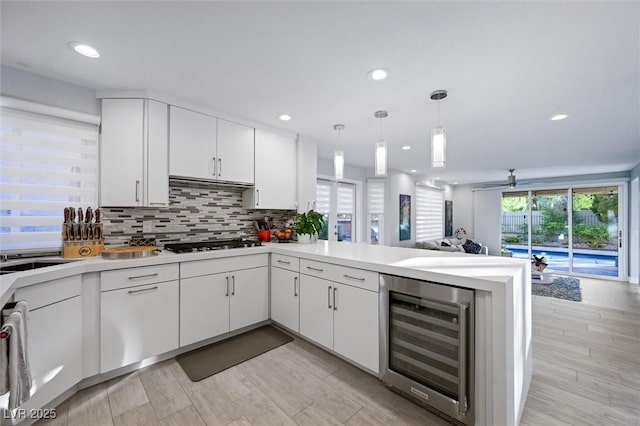 5125 Turnberry Ln, Las Vegas, NV 89113 - kitchen with wine cooler, gas cooktop, a peninsula, light countertops, and white cabinetry