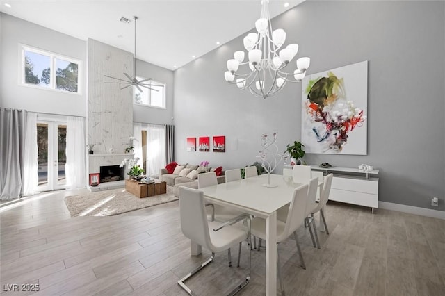 5125 Turnberry Ln, Las Vegas, NV 89113 - dining room featuring a high ceiling, a large fireplace, light wood-style floors, a chandelier, and a ceiling fan