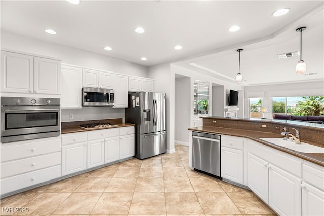 2069 Colvin Run Dr, Henderson, NV 89052 - kitchen with stainless steel appliances, a sink, dark countertops, hanging light fixtures, and white cabinetry