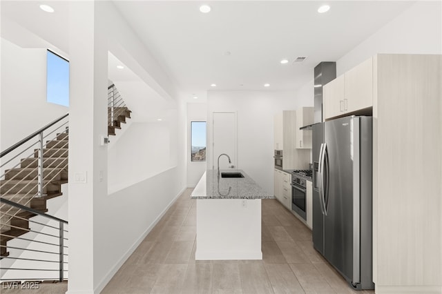 350 Solitude Peak Ln, Henderson, NV 89012 - kitchen featuring appliances with stainless steel finishes, a sink, a center island with sink, light stone counters, and wall chimney range hood