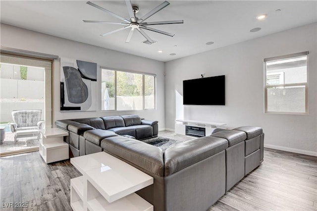 living room with a ceiling fan, light wood finished floors, baseboards, and recessed lighting