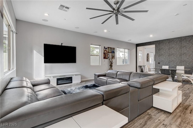 living room with light wood-style floors, a ceiling fan, recessed lighting, baseboards, and an accent wall