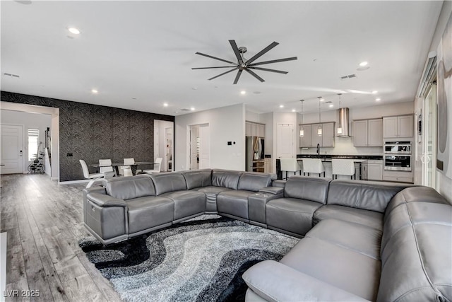 living area with ceiling fan, light wood-type flooring, recessed lighting, wallpapered walls, and baseboards