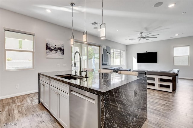 kitchen featuring dishwasher, a sink, a center island with sink, healthy amount of natural light, and recessed lighting