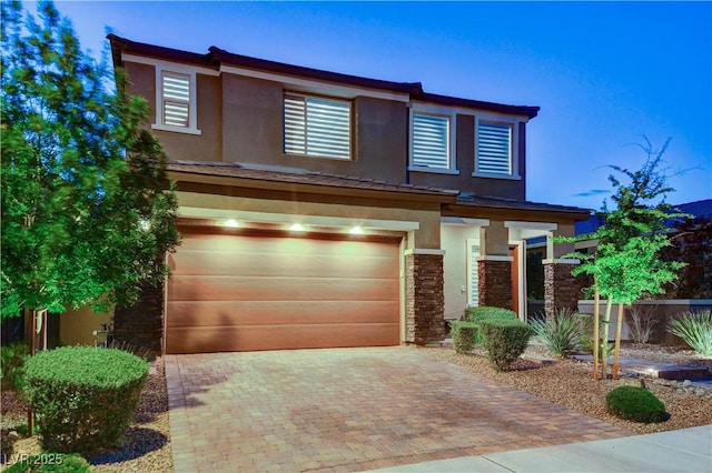 view of front of house featuring stucco siding, a garage, and decorative driveway