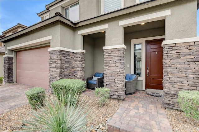 view of exterior entry with stucco siding, stone siding, decorative driveway, and a garage