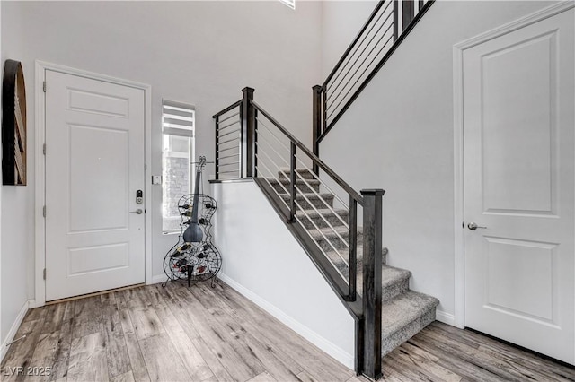 entryway with wood finished floors, baseboards, and stairs