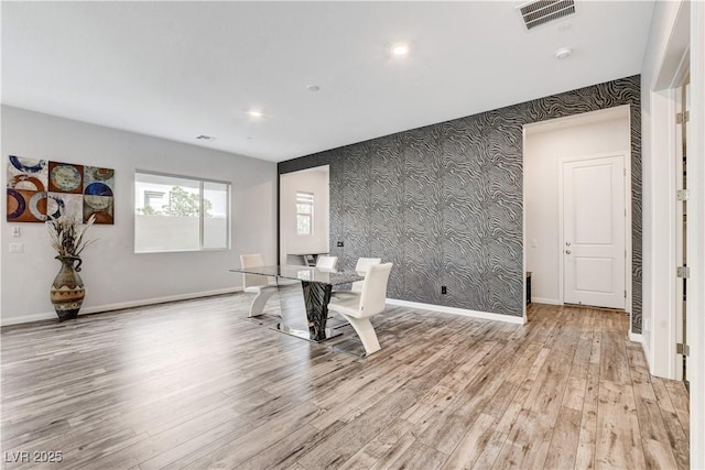 unfurnished dining area featuring wallpapered walls, light wood-style floors, baseboards, recessed lighting, and an accent wall