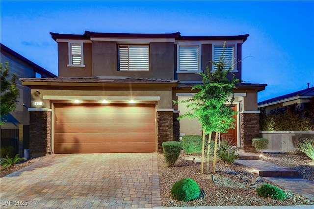 view of front of property with stucco siding, decorative driveway, a garage, and stone siding