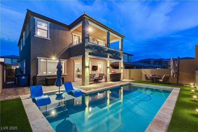 back of property with a balcony, a patio, and a fenced backyard
