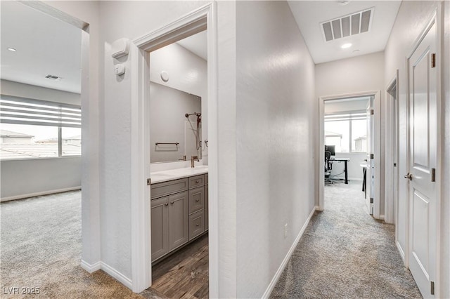 hallway with carpet, baseboards, and a desk
