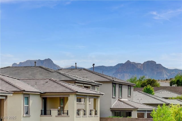 rear view of house with stucco siding, a tile roof, and a mountain view