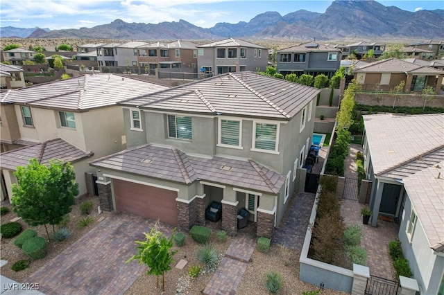 view of front of property with stucco siding, a residential view, stone siding, a mountain view, and decorative driveway