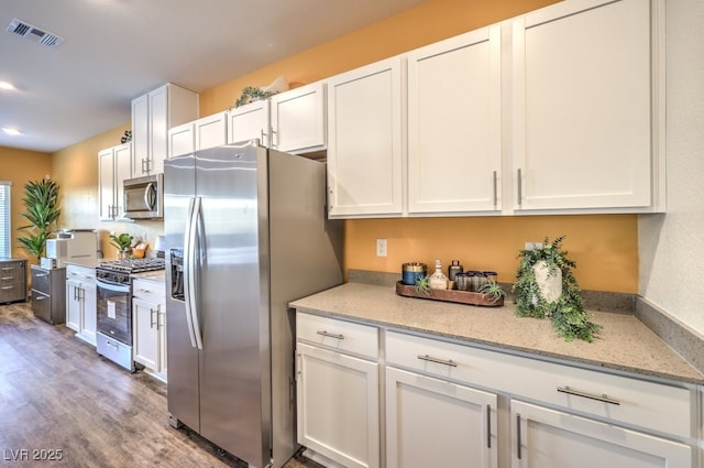 6521 Cinnamon Hazelnut St Lot 91, North Las Vegas, NV 89084 - kitchen featuring stainless steel appliances, white cabinets, wood finished floors, and light stone counters