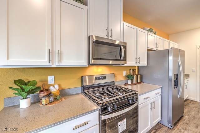 6521 Cinnamon Hazelnut St Lot 91, North Las Vegas, NV 89084 - kitchen featuring stainless steel appliances, white cabinets, light stone counters, and wood finished floors