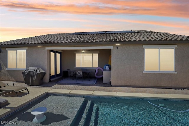 716 Cadence View Way, Henderson, NV 89011 - back of house with stucco siding, a tiled roof, roof mounted solar panels, and an outdoor pool