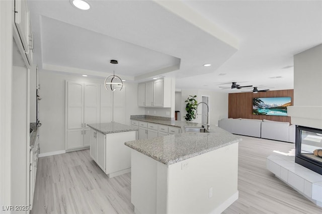 3604 N Campbell Rd, Las Vegas, NV 89129 - kitchen featuring a sink, a tray ceiling, a center island, light wood-style flooring, and recessed lighting