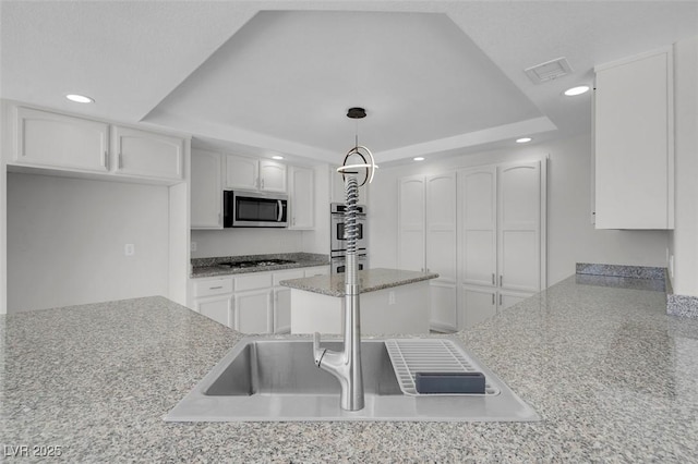 3604 N Campbell Rd, Las Vegas, NV 89129 - kitchen featuring a tray ceiling, appliances with stainless steel finishes, white cabinetry, recessed lighting, and decorative light fixtures
