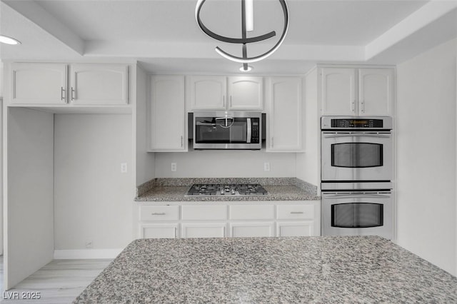 3604 N Campbell Rd, Las Vegas, NV 89129 - kitchen featuring appliances with stainless steel finishes, light stone counters, white cabinets, light wood finished floors, and baseboards