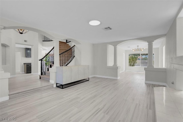 3604 N Campbell Rd, Las Vegas, NV 89129 - unfurnished living room featuring ornate columns, a chandelier, light wood-style floors, stairs, and baseboards