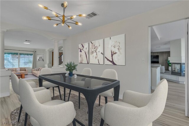 3604 N Campbell Rd, Las Vegas, NV 89129 - dining room featuring ornate columns, light wood-style flooring, a chandelier, and baseboards