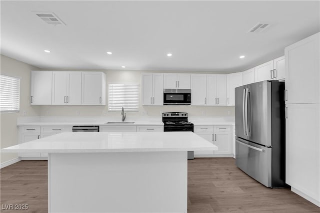 952 Balzar Ave, Las Vegas, NV 89106 - kitchen featuring stainless steel appliances, a sink, a center island, white cabinets, and light wood-style floors