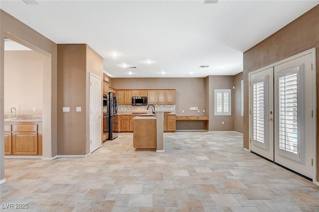 10608 Trussell St, Las Vegas, NV 89141 - kitchen with stainless steel microwave, stone finish floors, a kitchen island with sink, light countertops, and french doors