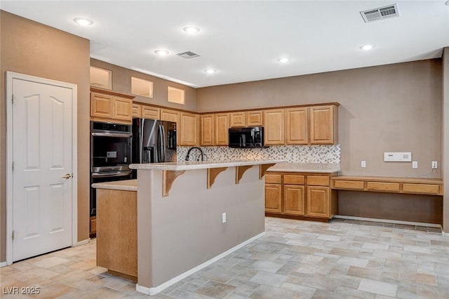 10608 Trussell St, Las Vegas, NV 89141 - kitchen featuring black appliances, a breakfast bar, light countertops, tasteful backsplash, and an island with sink