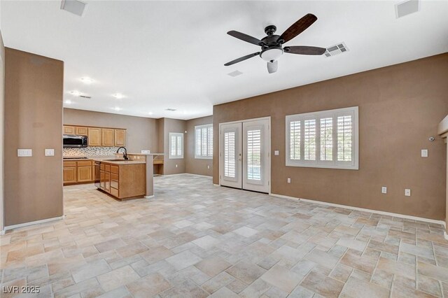 10608 Trussell St, Las Vegas, NV 89141 - kitchen with stainless steel microwave, open floor plan, stone finish floors, light countertops, and ceiling fan