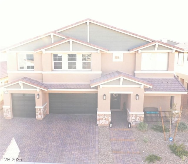 7855 Skyler Falls Ln, North Las Vegas, NV 89084 - view of front of house with stone siding, a garage, decorative driveway, stucco siding, and a tiled roof