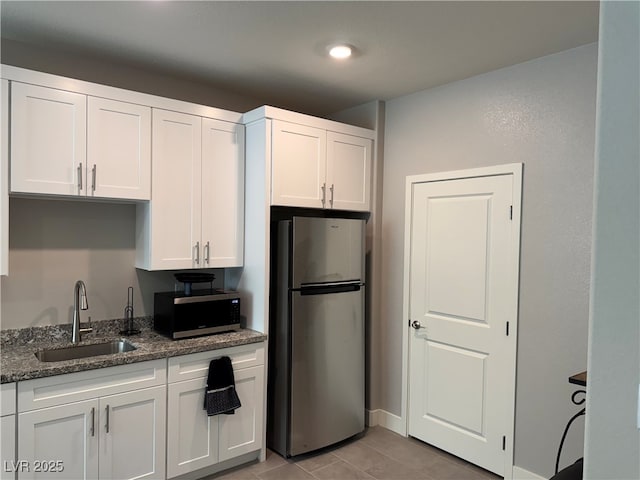 7855 Skyler Falls Ln, North Las Vegas, NV 89084 - kitchen with appliances with stainless steel finishes, white cabinetry, dark stone counters, and light tile patterned floors
